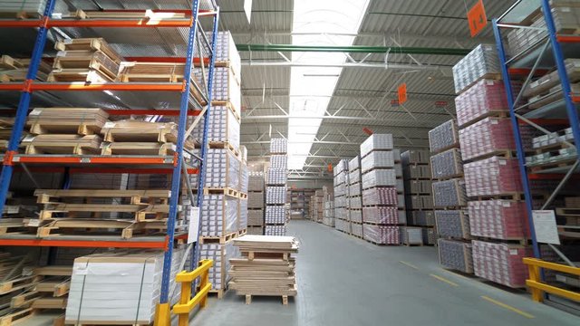 Shelves of warehouse are filled with parquet. Stock of woodworking factory. Camera motion to around