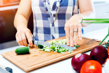 Female hands cutting cucumbers