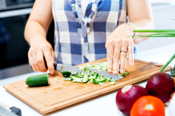 Female hands cutting cucumbers