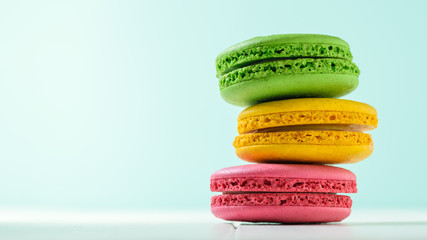 Macaroon cake red and yellow and green on a white wooden table on a blue background.