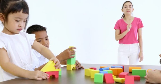 Close up scene video of Asian teacher lets Asian students playing colorful wooden blocks toy together, concept for classroom.