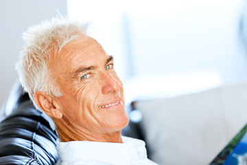 Fototapeta premium Handsome sennior man reading a book relaxing on a sofa