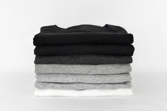 stack of folded black, grey and white color (monochrome) t-shirt on white background