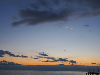 Evening sky after sunset above a sea and little trace of plane among clouds