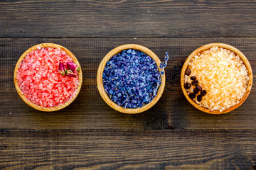 Colorful bath salt pink and blue on dark wooden background top view copy space