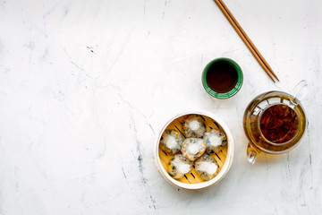Chinese food set with dim sum, sticks and tea on marble background top view copy space