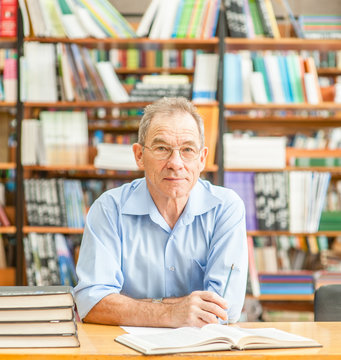 Happy senior man in the library looking at camera