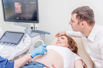 Obraz premium Happy couple looking at ultrasound results with doctor in hospital room