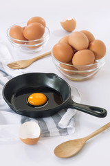 Raw eggs in a pan and egg bowl on a white background