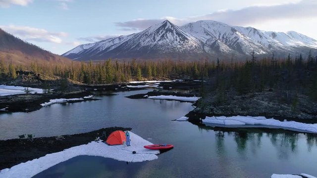 camera turning around a camping with hiker and his dog in mountains. aerial