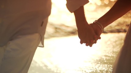Couple walking holding hands on beach
