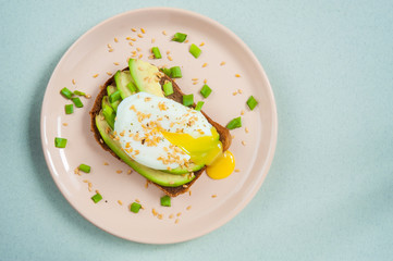 Toast with poached egg avocado and flax seeds on a pink plate. Healthy and tasty food. View from above. Copy space