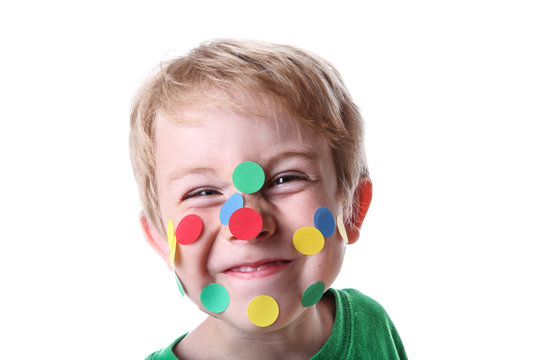 Smiling mischievous boy with round stickers on his face