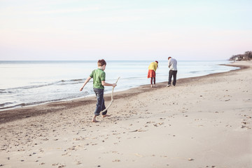 Boy walking down the beach with a walking stick