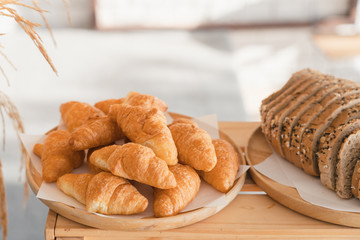 Slices bread and delicious croissant on wooden table background. Breakfast concept.