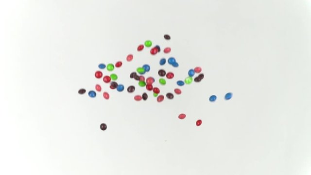 Oval color coated candies being tossed in the air; slow motion; repeat
