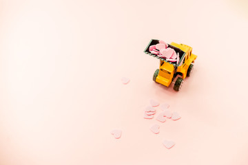 Yellow truck with pink Heart Confetti.Abstract background horizontal top view. Love Day COncept.