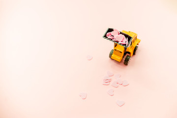 Obraz premium Yellow truck with pink Heart Confetti.Abstract background horizontal top view. Love Day COncept.