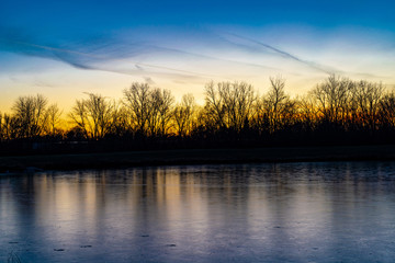 Sunset with frozen lake and trees