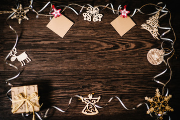 Blank, photo, instant, small paper hanging. Christmas tree ornaments, gift, box with ribbons, snowflakes, bells, deer, angel on a brown, structural wood background. flat lay. top view