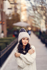 Cute brunette in a white sweater in a city