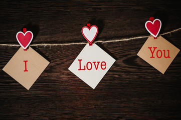 Text I love you. Craft paper, three blank, with red heart hanging on rope on brown wooden background with space. Place for text. concept of St. Valentine's Day. Women's Day, eighth of March.