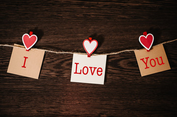 Text I love you. Craft paper, three blank, with red heart hanging on rope on brown wooden background with space. Place for text. concept of St. Valentine's Day. Women's Day, eighth of March.