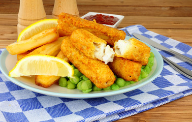 Fish fingers and chips meal with mushy peas on a wooden background