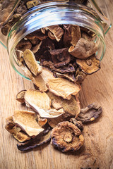 Dry mushrooms in jar on wooden table.