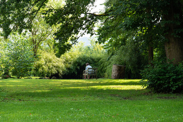A man sits on a bench in a park in a secluded place.