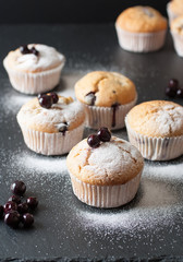 Sweet muffins with powdered sugar on black table