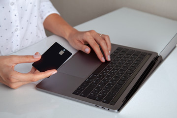 black credit card in beautiful hands of a girl in a white shirt on a white background