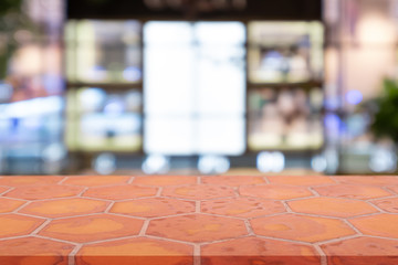 Perspective empty mon brick flooring (clay brick) over blurred shopping mall background, for product display montage or design layout.