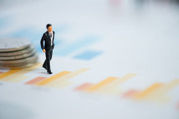 Miniature people businessman walk and analyze bar graph