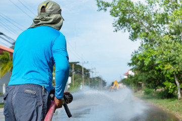a worker spraying water to clean the road with pressurized water system, wet cleaning of street