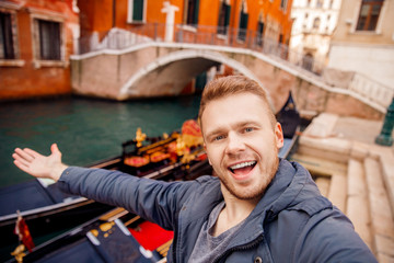 Happy tourist man makes selfie against background gondola in Grand Canal, Venice, Italy. © Parilov