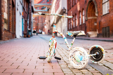 Colorful tricycle of a child stands alone and abandoned in the middle of a cobbled street