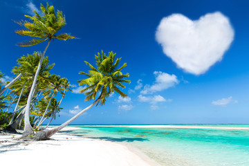 romantic getaway concept - tropical beach with palm trees and heart shaped cloud in french polynesia