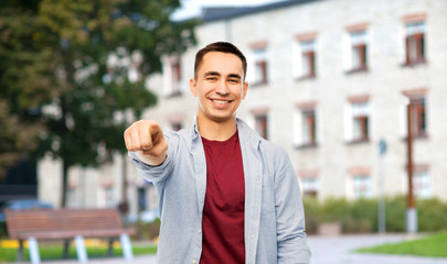 education, high school and people concept - man pointing finger to you over campus building background