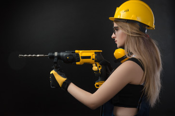 girl in construction clothes and protective equipment posing with a hammer