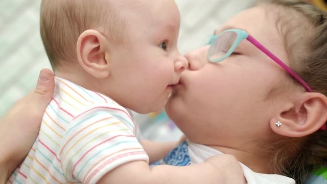 Happy sister kissing baby brother. Close up of girl kiss cute baby boy