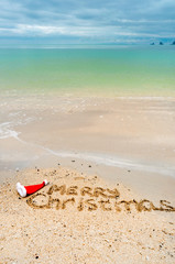 Fototapeta na wymiar Christmas holiday tropical vacation concept, Merry Christmas written on tropical beach sand and sea background 