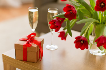 valentines day and romantic concept - gift box, champagne glasses and flowers on table
