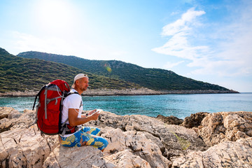 Happy traveler with a portable solar battery attached to his backpack