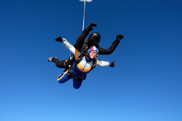 Obraz na płótnie Canvas Tandem skydiving. Girl-passenger is having fun in the sky.