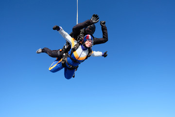 Obraz na płótnie Canvas Tandem skydiving. Girl-passenger is having fun in the sky.