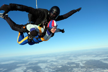Tandem skydiving. Girl-passenger is having fun in the sky.