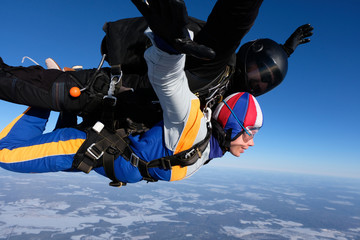 Tandem skydiving. Girl-passenger is having fun in the sky.