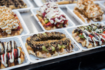 Different types of desserts and foods are being sold at a local shop. The closeup image of the foods being sold looks delicious. They are arranged in a proper order for display
