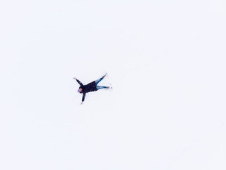 Aerial view of woman lying in snow making snow angel.